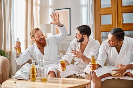 Three diverse men in bathrobes gather around a table, enjoying each others company while sharing drinks.