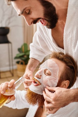 Two cheerful men in bathrobes enjoy a bonding moment as one gently putting mask on another mans face.