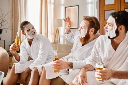 Photo for Three diverse cheerful men in bathrobes relaxing and enjoying each others company while sitting on top of a comfortable couch. - Royalty Free Image