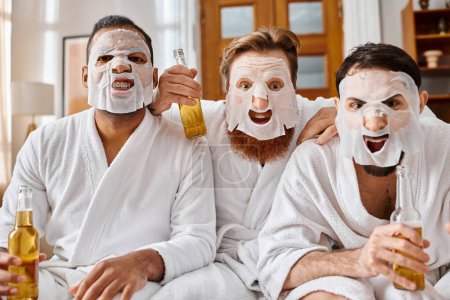 Three diverse men in bathrobes share a moment of joy wearing facial masks, symbolizing friendship and unity.