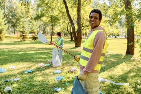 Socially active diverse loving couple in safety vests and gloves cleaning a park