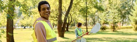Diverse couple in a bright yellow vests cleaning in a park.