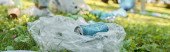 A can of soda rests on a plastic bag in the lush grass of a park, contrasting against the green backdrop. puzzle #703322634