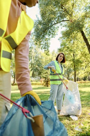 Diverse loving couple passionately cleaning up a park while wearing safety gloves.