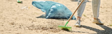 Una pala y una bolsa de polvo se colocan en una playa, mostrando las herramientas de una pareja socialmente activa limpiando el medio ambiente juntos.