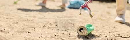 Eine erfrischende Dose Limo ruht sich am Sandstrand unter dem sonnenwarmen Schein aus, während diverse Paare den Strand reinigen.