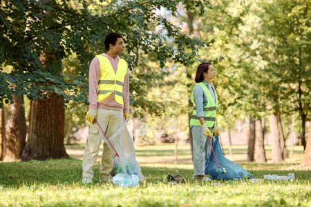 Photo for A socially active, diverse couple in safety vests and gloves cleaning the park together. - Royalty Free Image