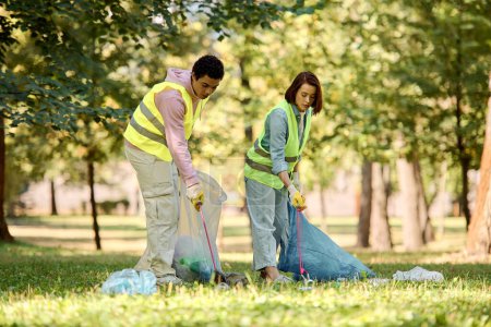 A socially active, diverse couple in safety vests and gloves stands united in the lush grass, passionately cleaning the park.