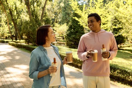 Foto de Una pareja en traje vibrante disfrutando del café juntos en un parque, expresando amor y unidad. - Imagen libre de derechos