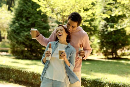 Téléchargez les photos : Un couple élégant en tenue vibrante dégustant un café ensemble dans un parc, créant une scène chaleureuse. - en image libre de droit