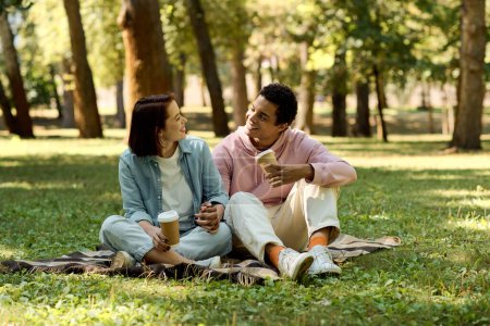 Una pareja diversa en traje vibrante disfrutando de una tarde tranquila en una manta en un parque.