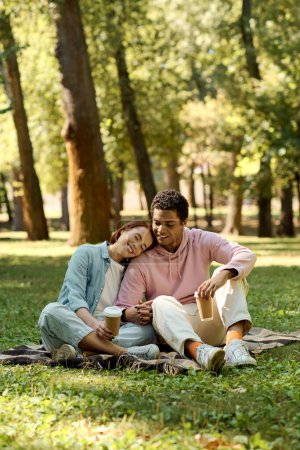 Ein Paar in lebendiger Kleidung sitzt auf einer Decke in einem Park und genießt an einem sonnigen Tag die Gesellschaft des anderen.