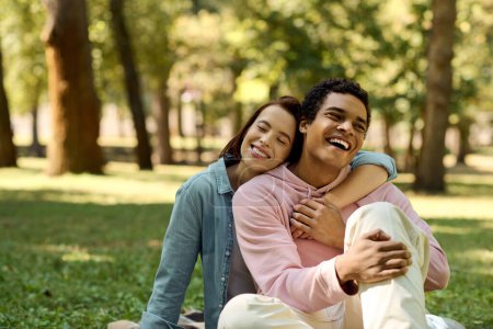 Téléchargez les photos : Un homme et une femme sont assis sur l'herbe dans un parc, vêtus de vêtements vibrants, s'embrassant dans un moment de sérénité. - en image libre de droit