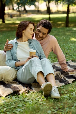 A man and woman in vibrant attire sit on a blanket in the park, enjoying each others company amidst the beauty of nature.