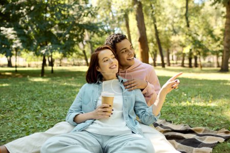 Ein lebendiges, vielfältiges Paar in bunten Gewändern sitzt auf einer Decke im Park und genießt einen ruhigen Moment zusammen.
