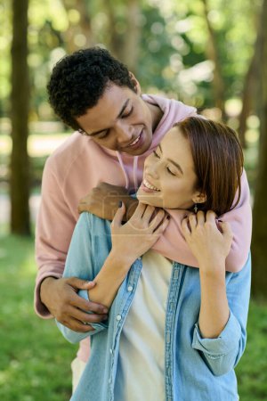 Foto de Un hombre vistiendo un atuendo vibrante sostiene a una mujer en un abrazo amoroso en un hermoso entorno de parque. - Imagen libre de derechos