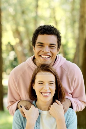 Una pareja diversa en traje vibrante sonriendo brillantemente para la cámara mientras disfrutan de un día juntos en el parque.