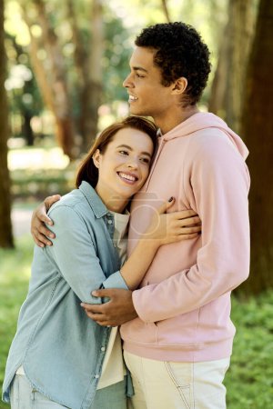 Foto de Un hombre en traje vibrante abraza tiernamente a una mujer en un parque, mostrando un momento de intimidad y conexión en un entorno natural. - Imagen libre de derechos