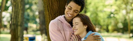 Téléchargez les photos : A diverse couple, dressed vibrantly, sharing a loving hug in a park setting. - en image libre de droit
