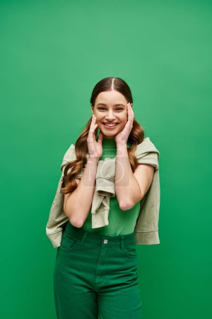 Téléchargez les photos : Une jeune femme élégante dans la vingtaine posant devant un fond vert luxuriant dans un décor de studio. - en image libre de droit