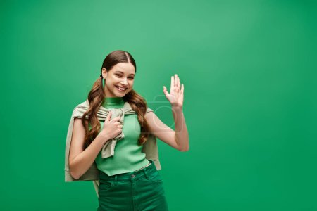 Foto de Una joven de unos 20 años se pone una llamativa camisa verde y pantalones a juego en un ambiente de estudio, exudando elegancia y estilo atemporal.. - Imagen libre de derechos