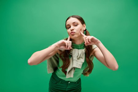 Foto de A young, beautiful woman in her 20s poses in a green shirt for a professional portrait in a stylish studio. - Imagen libre de derechos