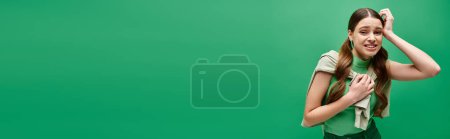 Téléchargez les photos : Confus jeune femme dans sa vingtaine se tient devant un fond vert vibrant. - en image libre de droit