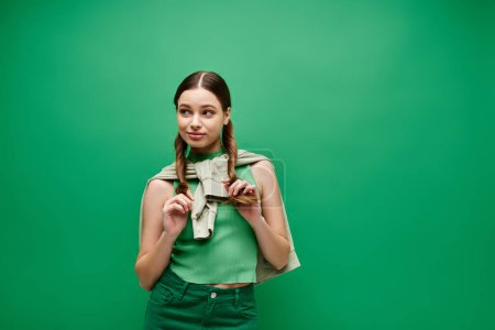 Téléchargez les photos : Une jeune femme dans la vingtaine avec de beaux cheveux longs posant dans un cadre de studio avec une toile de fond verte. - en image libre de droit