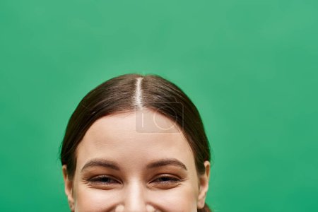 Photo for A young woman in her 20s, radiating joy with a captivating smiling eyes in a studio setting with a green background. - Royalty Free Image