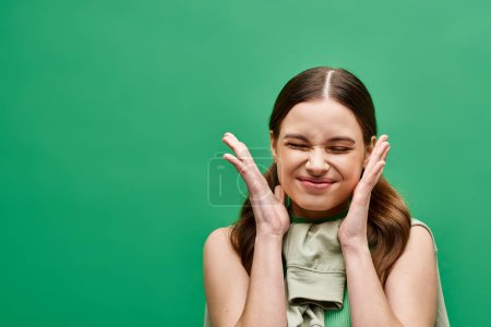 Photo for A young woman in her 20s stands with her hands near her face, revealing only glimpses of her beauty. - Royalty Free Image