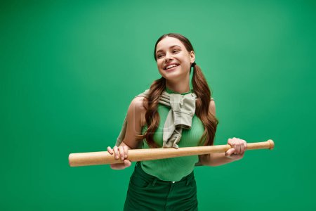 A woman in her 20s holds a baseball bat against a vibrant green backdrop, exuding strength and determination.