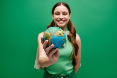 Une jeune femme d'une vingtaine d'années tient délicatement un petit globe dans ses mains, symbolisant les soins, l'unité et la connexion mondiale.