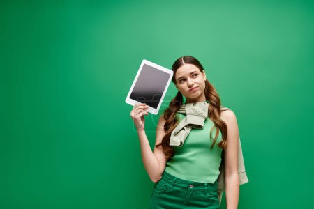 Eine junge schöne Frau in ihren Zwanzigern hält selbstbewusst einen Tablet-Computer in der Hand, der mit digitaler Kommunikation beschäftigt ist..