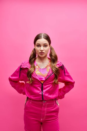 Photo for A stylish woman in her 20s strikes a confident pose in front of a vibrant pink background. - Royalty Free Image