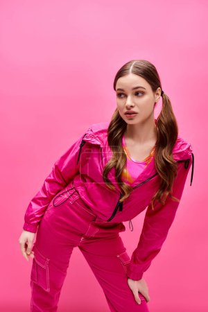 Foto de Una mujer joven y elegante de unos 20 años posa graciosamente frente a un fondo rosa. - Imagen libre de derechos