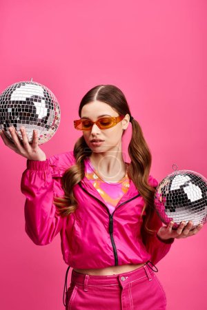 Mujer joven de 20 años sosteniendo dos bolas de discoteca frente a su cara, creando una imagen fascinante y elegante.