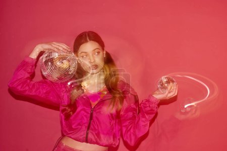 Foto de Mujer joven y elegante de unos 20 años que lleva un top rosa creando movimiento en un estudio con un fondo rosa. - Imagen libre de derechos