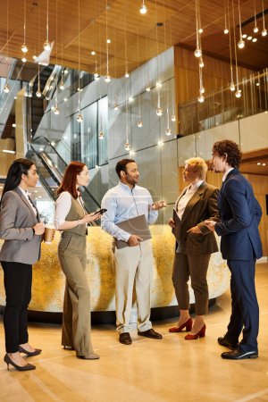 Photo for A diverse group of business people stand together in a modern lobby. - Royalty Free Image