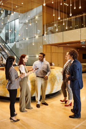 Un variado grupo de individuos de negocios que participan en una conversación en un elegante vestíbulo.