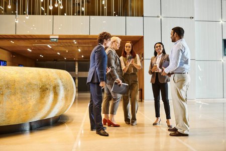 Foto de A diverse group of business people engaging in conversation in a lobby setting. - Imagen libre de derechos
