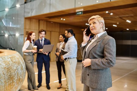 A woman stands in a lobby, engaged in a phone conversation.