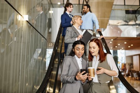 Téléchargez les photos : Multicultural business professionals confidently descend stairs together. - en image libre de droit