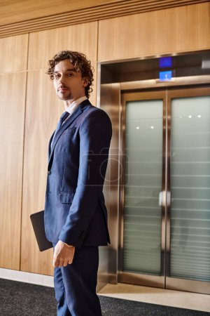 Foto de Un hombre de traje se para frente a un ascensor. - Imagen libre de derechos