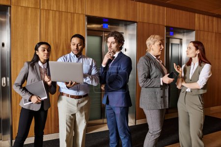 Multicultural business professionals stand poised in front of elevator doors.