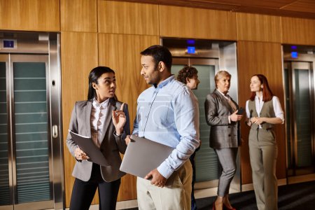 Téléchargez les photos : A diverse group of business people standing together in front of several elevators. - en image libre de droit