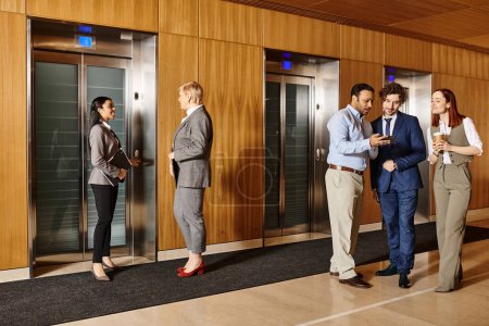 Profesionales de negocios multiculturales de pie juntos frente a ascensores.