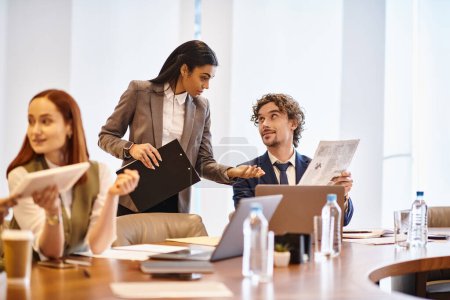 Téléchargez les photos : An interracial group of business professionals engaged in a meeting around a conference table. - en image libre de droit