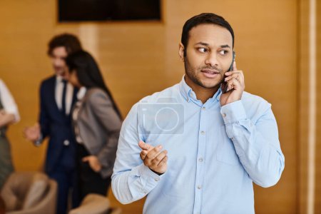 Photo for A man in a blue shirt engages in a phone call with a focused expression. - Royalty Free Image