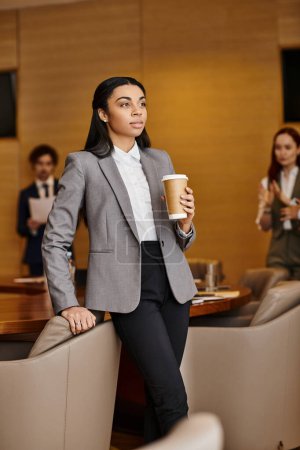 Foto de An African American woman in a business suit holding a cup of coffee. - Imagen libre de derechos
