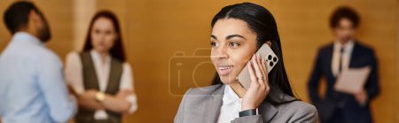 Una mujer habla en un teléfono celular frente a un grupo diverso de empresarios.
